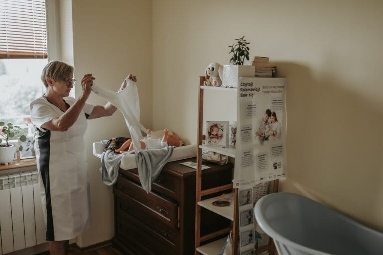 Położna Halina Siwińska podczas zajęć w szkole rodzenia w Skierniewicach pokazuje rodzicom technikę przewijania noworodka